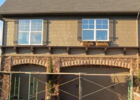 Home with scaffolding and new siding being placed